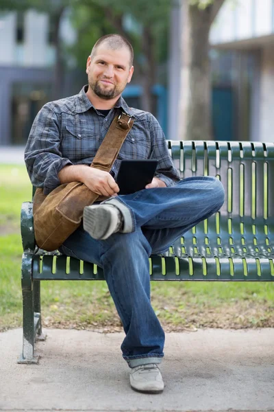 Confident Male Student Sitting On Bench At Campus