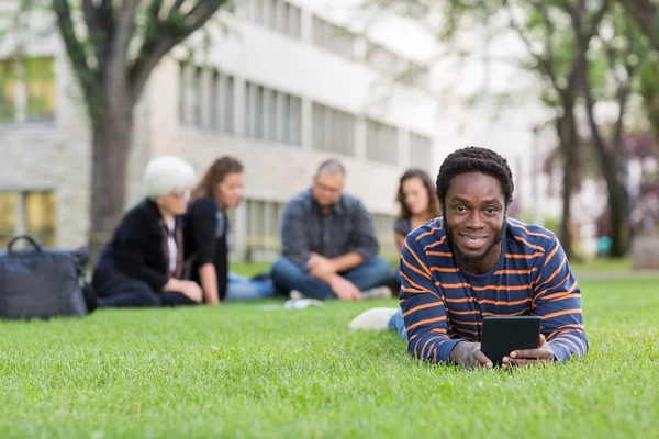 Student With Digital Tablet On Grass At Campus Park