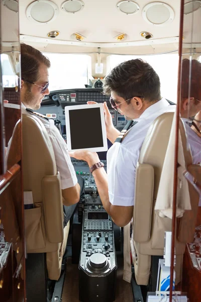 Pilot Showing Digital Tablet To Copilot In Cockpit