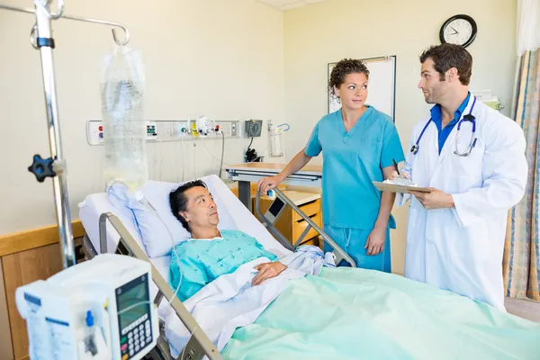 Medical Team Looking At Each Other While Patient On Bed