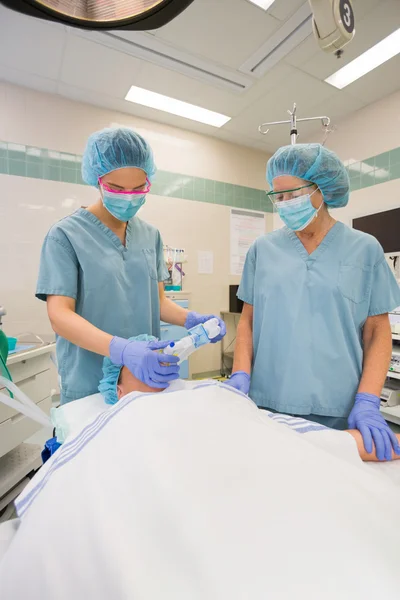 Nurses Adjusting Oxygen Mask On Patient