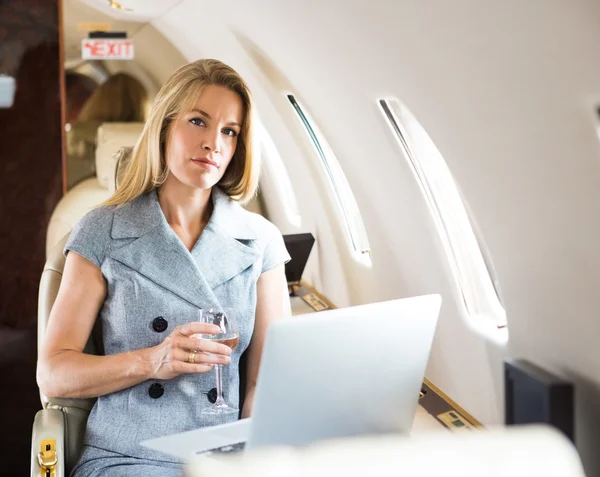 Confident Businesswoman Holding Wineglass In Private Jet