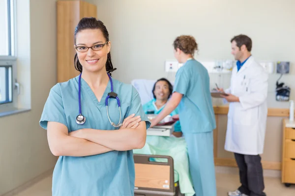 Confident Nurse Against Patient And Medical Team At Hospital