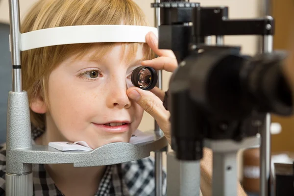 Optician's Hand Checking Boy's Eye With Lens