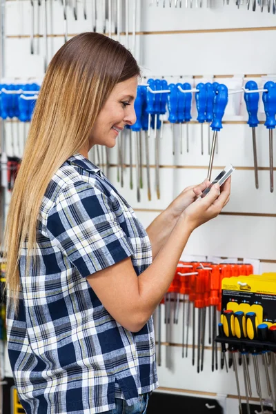 Woman Checking Information Of Screwdriver On Mobilephone