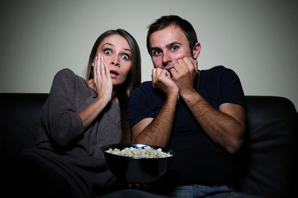 Young couple watching scary movie on tv