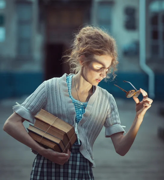 Funny girl student with books and glasses and a vintage dress