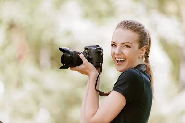 Smiling young woman photographs on camera
