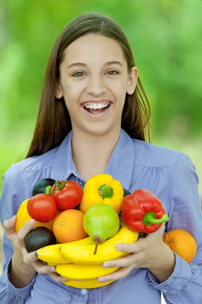 Teenage girl holding banana, peppers, pears and oranges