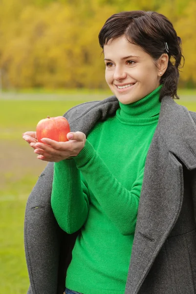 Smiling cute woman bites ripe apple