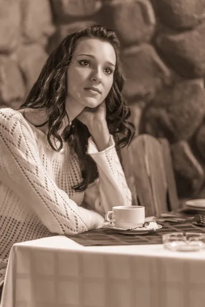 Young beautiful woman sits in cafe