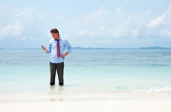 Business man calling by cell phone on the beach