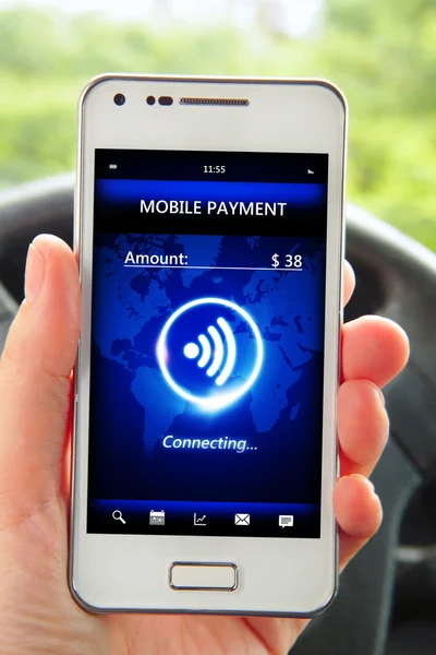 Hand holding smartphone with mobile payment in the car