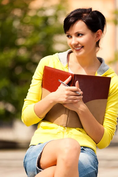 Student young woman with notebook, outside