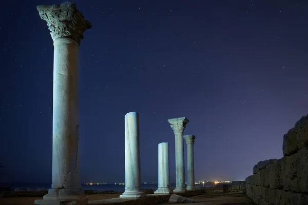 Ruins of ancient city columns under night sky
