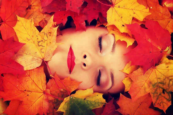 Woman face in autumn leafs