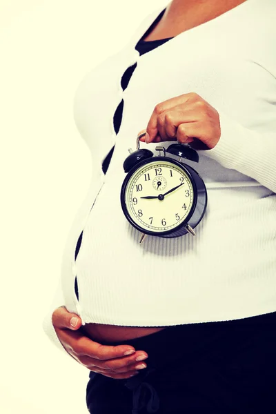 Pregnant woman holding alarm clock