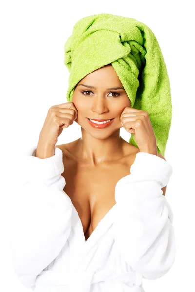 Woman wrapped in towel, holding her mouth in a smile.