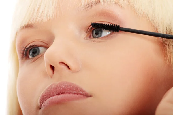 Woman doing make up on eyelashes.