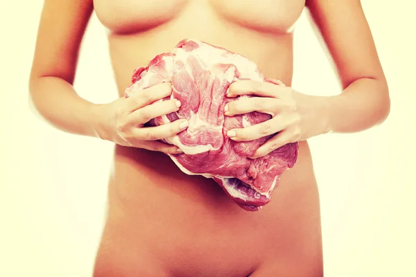 Nude woman holding big part of raw meat pork neck.