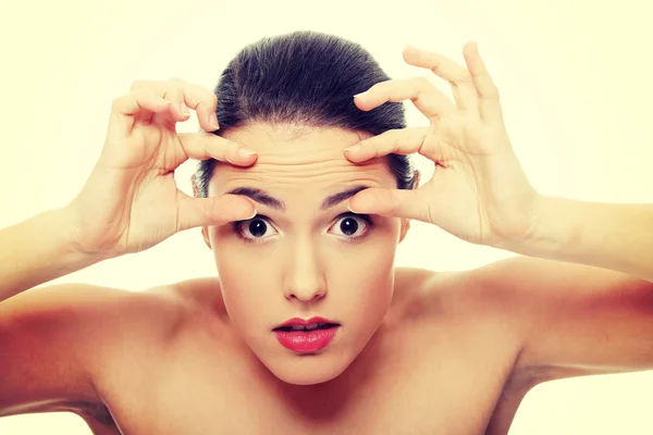 Woman checking her wrinkles on her forehead