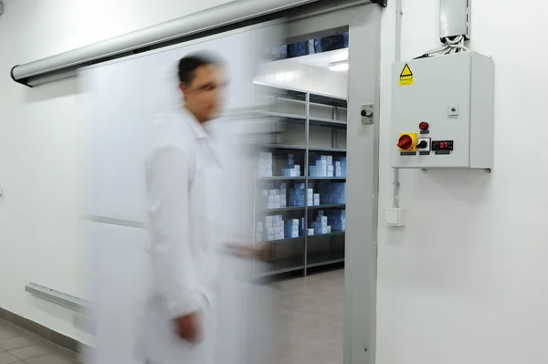 Young worker opening door of industrial refrigerator, blurred motion