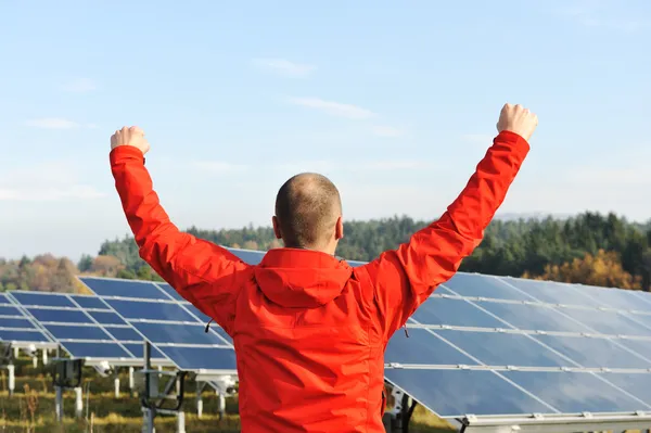 Success, engineer in solar panel fields with arms up