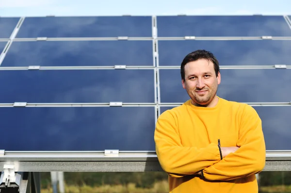 Young male engineer with solar panels in background