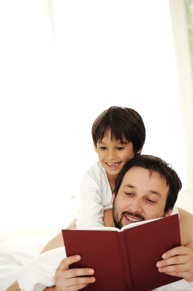 Father and son in bed, reading book together