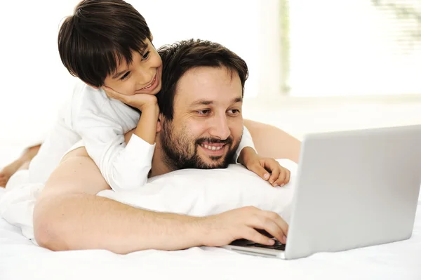 Father and son in bed, using laptop together, happy time