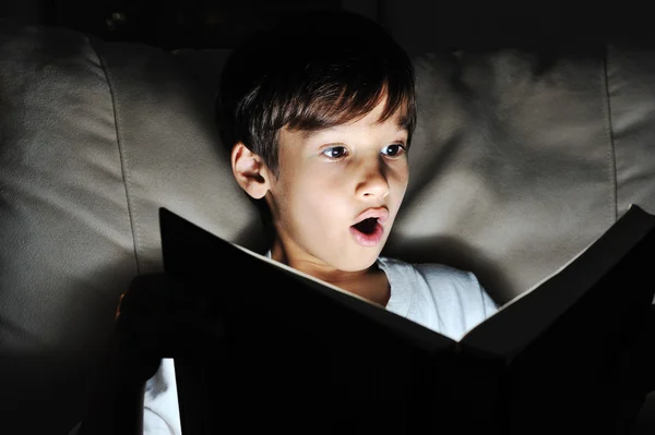 Shocked kid reading book, light in darkness