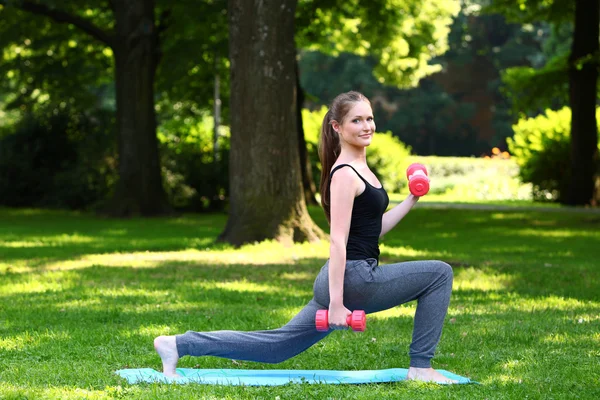 Young woman doing lunges with dumbbells