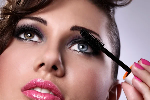 Beautiful woman face with mascara brush