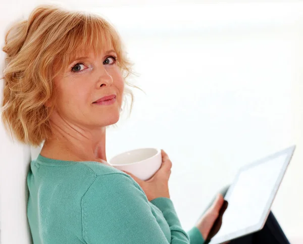 Middle age woman relaxing with tablet comper