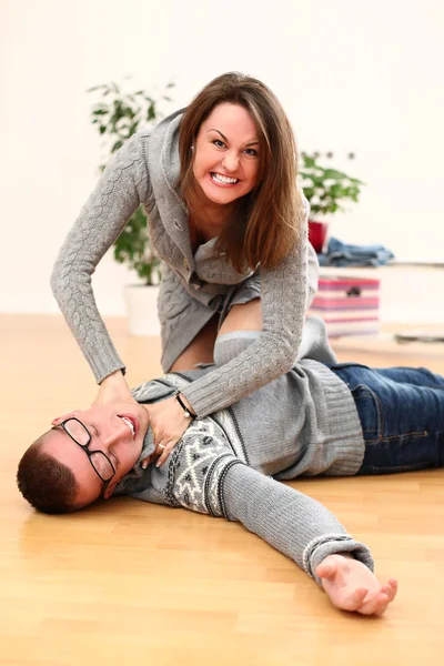 Angry woman choking a man lying on a floor