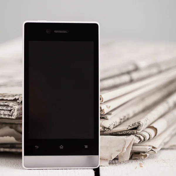 Pile of newspapers with smartphone on it