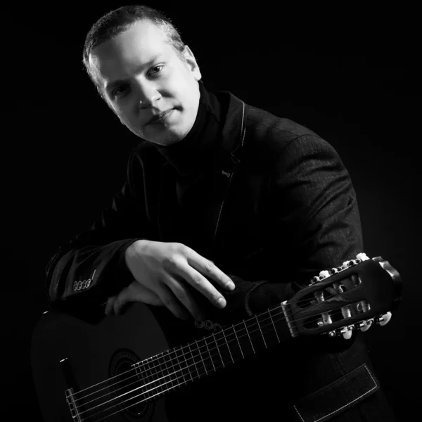 Musician in black suit holding guitar