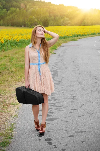 Woman with vilolin case by country road