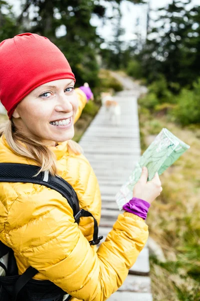 Woman hiking and reading map in forest