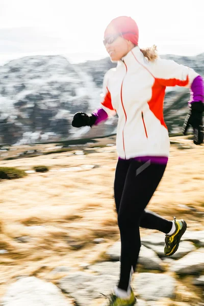 Young woman running in mountains on winter fall sunny day