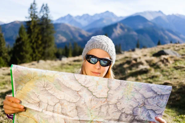 Woman hiker reading map in mountains