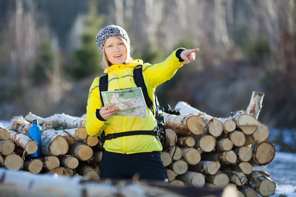 Woman hiking in winter forest with map