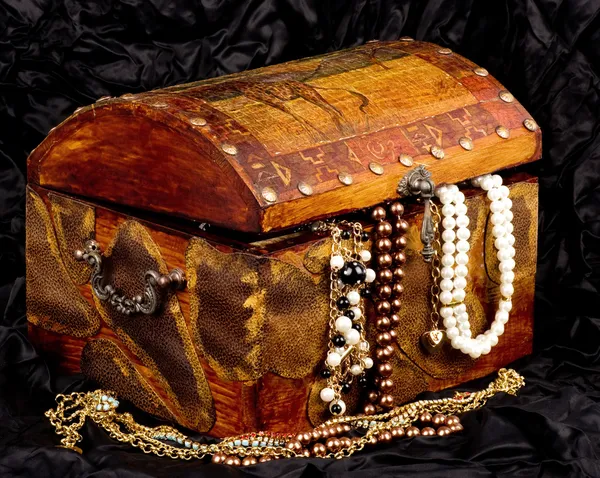 Old wooden open chest with golden jewelry