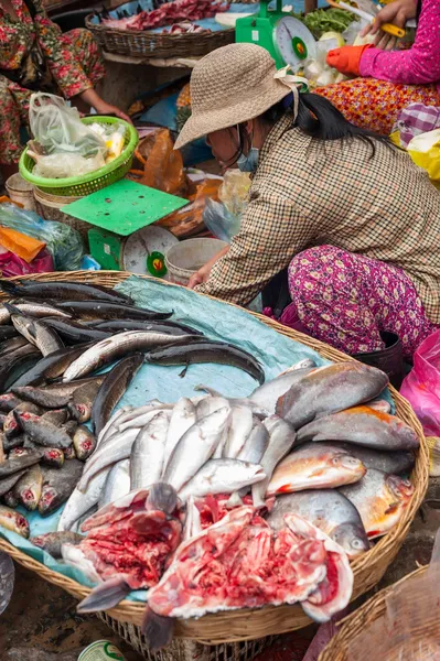 Khmer woman cleaning and selling fish at food marketplace in Siem Reap, Cambodia