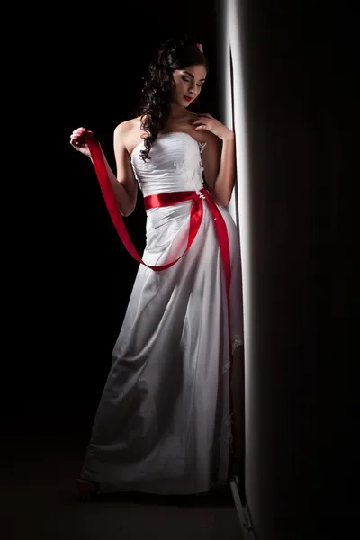 Bride in a white dress with a red ribbon