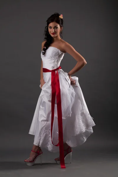 Bride in a white dress with a red ribbon