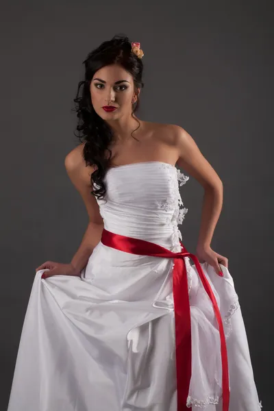 Bride in a white dress with a red ribbon