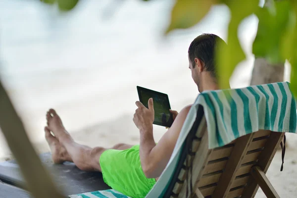 Man ralaxing and use tablet at beach