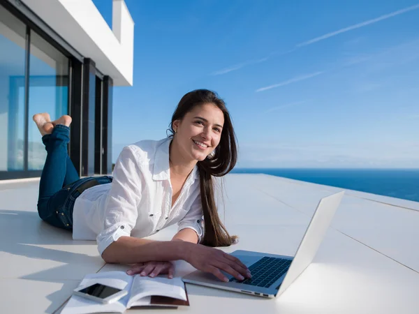 Relaxed young woman at home working on laptop