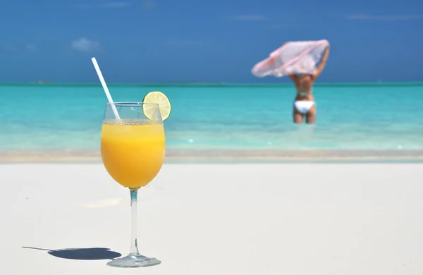 Glass of orange juice on the sandy beach of Exuma, Bahamas